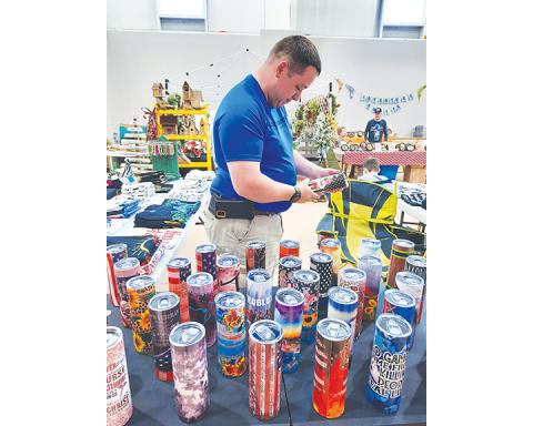 Eric Spalding looks at tumblers and mugs created by vendors Christina Brown and Jennifer Spalding during the First Free Will Baptist Church Arts & Craft show in Hayesville