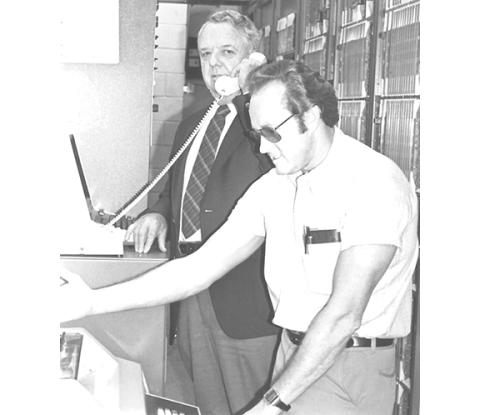 Mayor Ty Burnette (back) is testing the new equipment in the Telephone Exchange Building in Andrews during the early 1970s. George Postell (front) was the technician/supervisor overseeing the process of changing to private telephone lines.