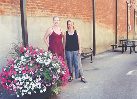 Downtown development director Laura LaChance (right) and town council member Keisha Dockery stand in the alley complete with fairy lights, benches and tables.