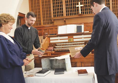 The Rev. Will Posey, church historian Charlene Smith and the Rev. Thomas Stubbs, a former pastoral intern, prepare Murphy First United Methodist Church’s time capsule items before they are sealed in the box for 100 years.