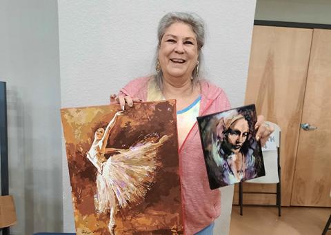 Mimi Hitselberger holds a paint-by-numbers painting of a ballerina along with a painting she did prior to her medical issues.