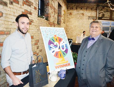 Photos by Abigail Blythe Batton/Staff Correspondent  Jesse James and Trevis Hicks (right) stand by the fundraising wheel during HAVEN Children’s Advocacy Center’s annual $5,000 raffle Saturday night at the Hackney Warehouse. 