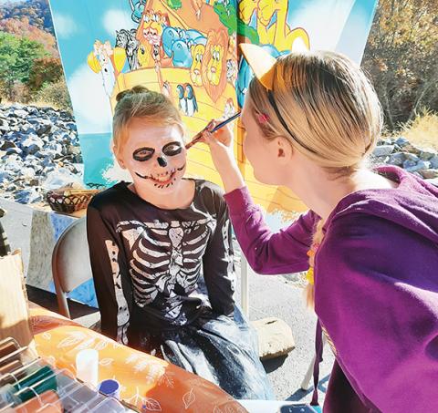 Anngee Quinones-Belian/Staff Correspondent Willow Crisp has her face painted by Hope Ledford during Shepherd of the Mountains’ Trunk or Treat event Saturday in Murphy. More photos, page 10A.