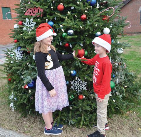 Photos by Abigail Blythe Batton/Staff Correspondent Izabella McLeod (10) and Andrews Elementary School second-grader Landon Burney (8) play by the town Christmas tree before the parade on Dec. 10.