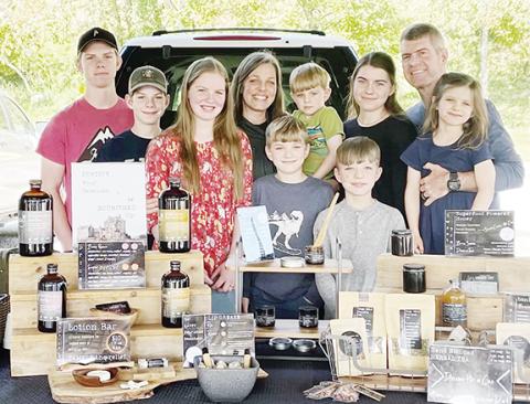 From left are Titus, Thaddeus, Charity, Hope (holding Asher), Chloe, Robbie (holding Charlotte), Benjamin and Isaiah Ellison of Andrews with Elderberry products and more.