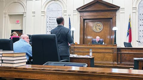 Randy Foster/editor@cherokeescout.com  Murder defendant Bryan Crisp (left) sits with his lawyer, Bill Jones, as assistant district attorney John Hindsman Jr. shows the jury a photo of the crime scene Monday at the Cherokee County Courthouse in downtown Murphy.