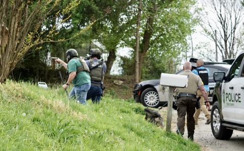Two lawmen, left, take point with more than a dozen officers and K-9 support behind them as they approach a Fort Butler Street residence in Murphy on Thursday, April 13, 2023.