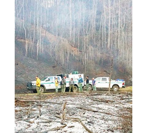Randy Foster/editor@cherokeescout.com  Firefighters take a breather after containing a 10-acre woods fire near Granny Squirrel off U.S. 19 on Friday. The fire was caused when someone set fire to a pile of tires.