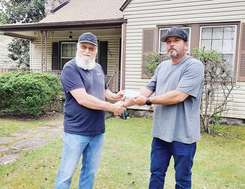 Anngee Quinones-Belian/Staff Correspondent  David Thomas presents Eddie Eller with a check from the community for Keith Ledford’s new roof, thanks to donations from the community and a gofundme.com fundraiser. 