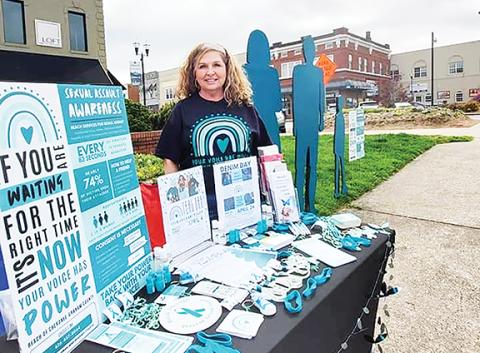 Reach advocate Kimberly Stiles stands next to one of the informational tables situated in front of the teal silhouette sculpture as part of the group’s efforts to educate the community during Sexual Assault Awareness Month in April.