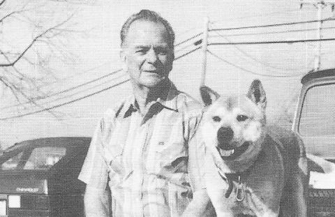 Sam Webb and his dog, Stormy, sitting on the back of his old Chevrolet truck at the post office parking lot in the 1990s.