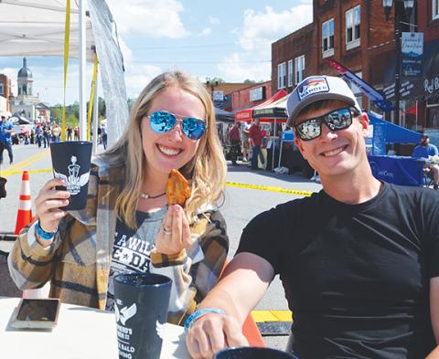 Abigail Blythe Batton/Staff Correspondent Adria Jones – sitting for a spell with her husband, Loren Jones – holds up a beer and a chicken wing in the VIP section of Murphy Music & Brews, a fundraising festival held downtown on April 22 to raise money and awareness for Shepherd’s Men and the Shepherd Clinic in Atlanta, which treats injured U.S. military veterans. Southern rock band Drivin N Cryin played at the show.