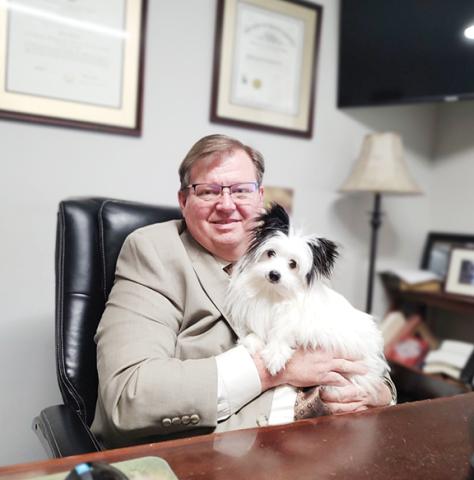 Abigail Blythe Batton/Staff Correspondent Rich Cassady sits at his desk with Lucy, his beloved “palmapoo” – his term for a Pomeranian poodle mix – during a busy day as an area defense attorney.