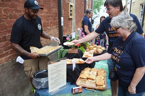 Abigail Blythe Batton/Staff Correspondent Mason Bar chef Andre Brookins serves food to Cecilia Crawford, executive director of Reach of Cherokee County and president of the Rotary Club of Murphy, and Rotarian Jim Gerke at the AfterHours event sponsored by the Cherokee County Chamber of Commerce in Fain Alley on June 29.