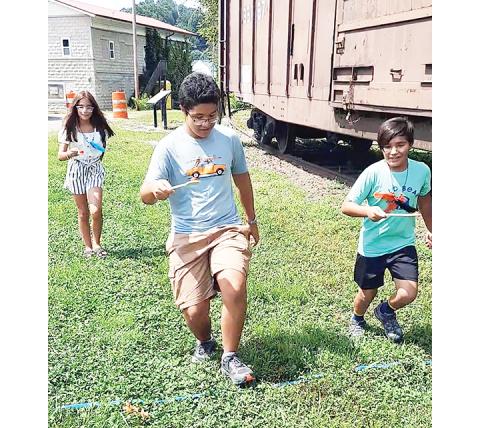 Gabriela, David and Santiago Barillas competed in the tomato relay race at the Murphy Farmers Market. David (center) took the first-place ribbon, while Gabriela (left) took second place and Santiago (right) walked away with third Saturday.