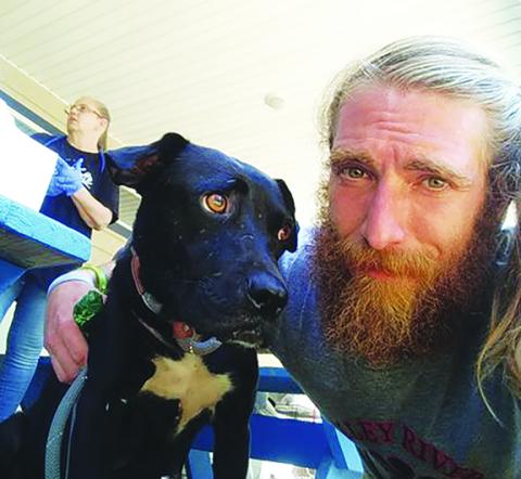 Valley River Humane Society kennel manager Hunter Drewry poses with one of dozens of dogs removed from a property near Andrews on Friday.