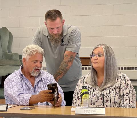Andrews Mayor James Reid, Cherokee County school board member Steve Coleman and Andrews Mayor Pro Tem Brandi Smith hold a sidebar discussion following Coleman’s presentation of his school consolidation plan in Andrews on July 25.