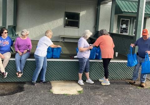 Volunteers prepare to hand out bags of food as vehicles pass by the outdoor pavilion at the Brasstown Community Center.