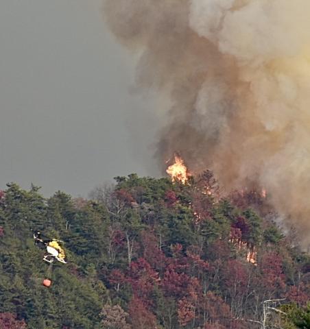 Fire as seen from Pisgah Road. Notice the helicopter approaching from the lower right preparing to drop water on the blaze. 