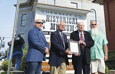 Randy Foster/editor@cherokeescout.com Cherokee County Manager Randy Wiggins, Commissioner Cal Stiles, former county manager Ron Hill and Commissioner Randy Phillips (from left) pose outside with an award in Hill’s honor  at the Cherokee County Historical Museum in Murphy on Oct. 5.