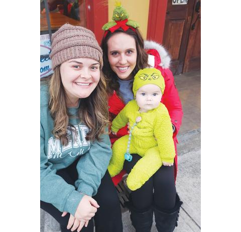 Nicole Wright/Staff  Correspondent Mackenzie, Hailey and Tate Rogers as the cutest baby Grinch wait with anticipation for the Andrews Christmas Parade to start Saturday evening downtown. The parade was delayed for a week, but the good-size crowd didn’t seem bothered in the least.