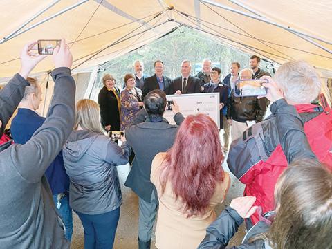 Randy Foster/editor@cherokeescout.com Attendees record the moment as local and state dignitaries pose with a symbolic check on Friday during a groundbreaking ceremony for Valley River Apartments, a 56-unit, low-cost apartment complex that will be built behind Walmart in Murphy.