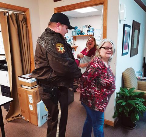 Anngee Quinones-Belian/Staff Correspondent Cherokee County sheriff’s Deputy Tim Leslie arrests Reach of Cherokee-Graham County Executive Director Cecilia Crawford-Faulkner on March 1 as Women’s Resource Center coordinator/court advocate Amanda Hamby looks on with what looks like lots of laughter.