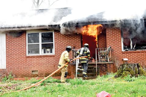 Becky Long/Clay County Progress Firefighters move in closer to assess the situation amid smoldering eaves and flames still billowing from the interior front entrance way and window on April 1. The fire was contained, but the house was most likely destroyed from the damages.