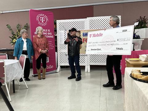 David Brown/dbrown@cherokeescout.com Ray Calles, retail store manager for T-Mobile, talks about the Sharing Center’s $19,996 grant Thursday afternoon in the Murphy First Baptist Church Fellowship Hall. To his left (from left) are grant writer Karen Borchers and food bank board President Sande Kimball; to his right is board vice president Steve Runyan, holding the big check.