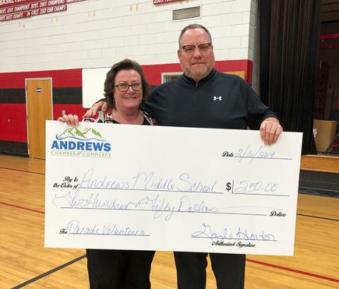 Then Andrews Middle School principal Lance Bristol accepts a $250 donation from Andrews Chamber of Commerce President Gayle Horton in 2019.