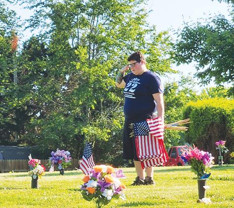 Paulette Smithmeyer/ Contributing Photographer Melissa Van Keuren salutes a fallen soldier at Greenlawn Cemetery in Peachtree on Friday. American Legion Post 96, along with Auxiliary Unit 96 and Warriors Veteran Outreach in Murphy, place flags at the cemetery in honor of the U.S. military’s fallen soldiers. For many years, Post 96 has headed up the effort to place flags on the Friday before Memorial Day, when each name is also read and saluted.