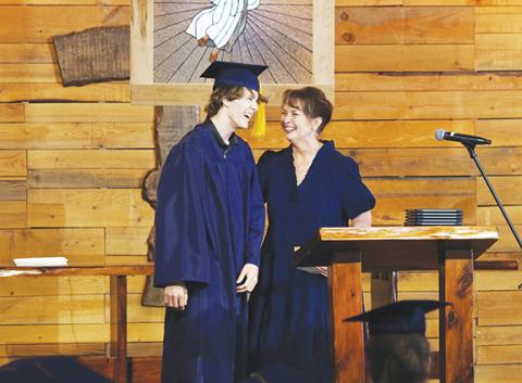 Cannon Crompton/sports@cherokeescout.com Issiah Hall (left) receives the Steve Bias Scholarship from Oaks Academy Principal Carmen Garland during commencement ceremonies Thursday.
