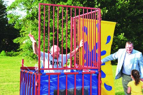 Photos by Anngee Quinones-Belian/Staff Correspondent  Murphy Police Chief Tim Lominac goes down into the water during National Night Out on Aug. 6 at the hand of Mayor Tim Radford, who helped a youngster hit the target.