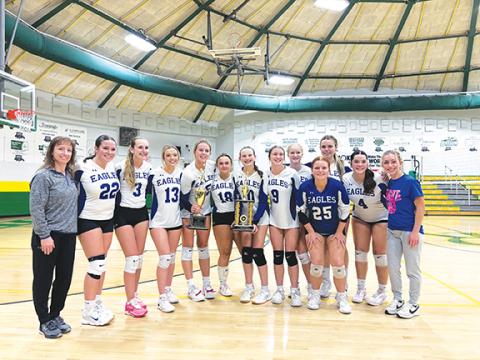 April McNabb/Contributing Photographer  Hiwassee Dam varsity volleyball players proudly hold their Little Smoky Mountain Conference championship trophy after defeating Highlands on Oct. 16. From left are head coach Angie Davis, Avery McNabb, Gracie Rhodes, Brooklyn Orton, Olivia McNabb, Ally Ledford, Abby Harris, Autumn Kamaras, Kinley Stiles, Bella Stiles, Addison Stiles, Brinkley Payne and assistant coach Kellee Davis.