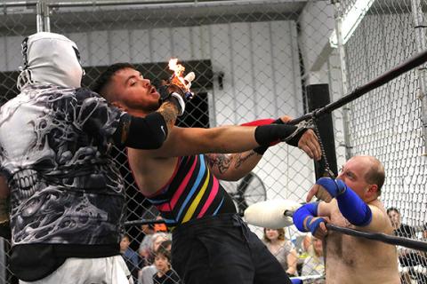 Cannon Crompton/sports@cherokeescout.com The Ghost holds his flaming hand in front of Flex Ferguson as he is handcuffed to Frodo at ACWF Cage Wars on Oct. 5.