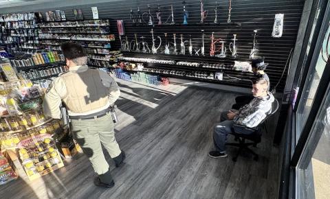 An unidentified law enforcement officer stands by, left, over two men taken into custody at a drug raid at  Tobacco & Vape store off Andrews Road in Murphy on Friday afternoon. Shown in custody are Ayab Alsalmp, 25, of Detroit, foreground right, and Wyle Radwan Alsalme, 21, of 1508 Andrews Road, Murphy, background right. Alsalmp was released without bail or charges, while Alsalme was charged with possession of a Schedule I controlled substance and released in lieu of $10,000 bond. 