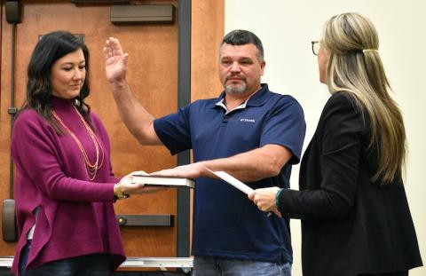 Randy Foster/editor@cherokeescout.com Newly elected Cherokee County Commissioner Alan Bryant takes the oath of office Monday, flanked by his wife, Marla (left) and Maria Hass, who administered the oath.