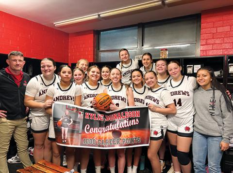 Misty Wood/Contributing Photographer Andrews senior Kylie Donaldson (middle, with basketball) is joined by her teammates and coach to celebrate her hitting the milestone of 1,000 points in her high school career.