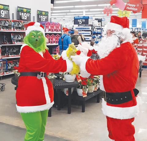 Anngee Quinones-Belian/Staff Correspondent  Santa Claus meets the Grinch: The Grinch was behaving nicely at Walmart in Murphy during Shop With a Cop on the morning of Dec. 14, even appearing to exchange gifts with Santa.