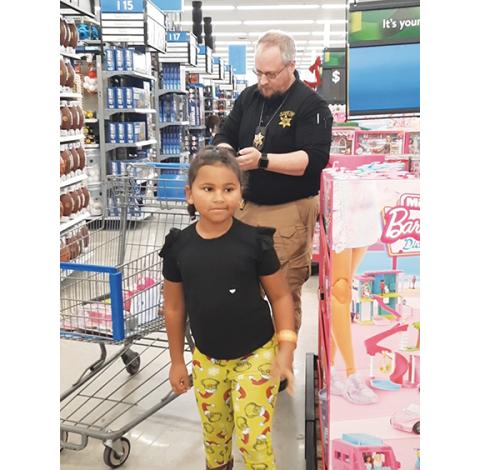Photos by Anngee Quinones-Belian/Staff Correspondent Detective Jason Hall with the Cherokee County Sheriff’s Office was busy totaling up the items Katherine was picking out under the Shop With a Cop Program. All the fun happened at Walmart in Murphy on Saturday morning.