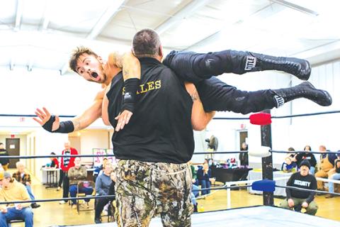 Cannon Crompton/sports@cherokeescout.com Mountain Man Jeremy Stiles catches Flex Ferguson after his jumps off the ropes before Stiles slams Flex into the mat in their match Saturday night at the Peachtree Community Center.