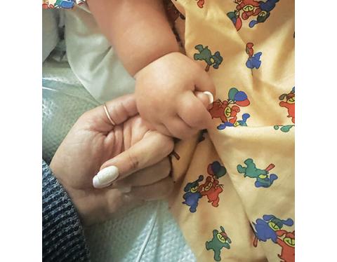Peyton Mixon holds the finger of her mother, Jordan.