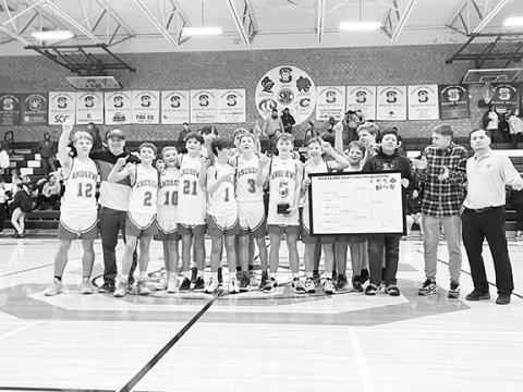 The Andrews Middle School basketball team proudly stands on the court with their conference championship trophy on Jan. 30.