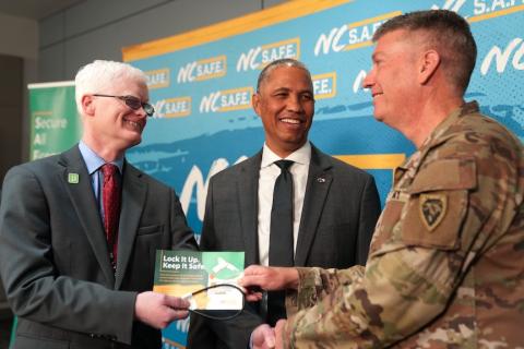Lock ’em up: The N.C. Department of Public Safety’s deputy secretary for juvenile justice and delinquency prevention, William Lassiter (left) – accompanied by Secretary Eddie Buffaloe Jr. (center) – presents a gun lock to N.C. National Guard Brigadier Gen. Charles Morrison (right). The Secure All Firearms Effectively Campaign has provided 10,000 gun locks to the National Guard’s Integrated Primary Prevention team in an effort to reduce self-harm and offer safe firearm storage options for their families. 