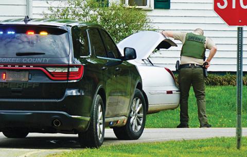 Randy Foster/editor@cherokeescout.com A Cherokee County sheriff’s deputy, his hand gripping his sidearm, checks the trunk of a car at the intersection of Airport and IOI roads in Marble on Thursday during a search for an escaped inmate.