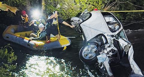 Photos by Graham County Fire & Rescue Above: Members of Graham County Fire & Rescue work their way back to shore after rescuing Dr. James Vollmer of Andrews following an accident that sent Vollmer into the Cheoah River on May 13. Below: Vollmer sits atop his vehicle waiting for assistance.