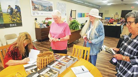 Nicole Wright/Staff Correspondent Local author and columnist Kandy Barnard signs copies of her book The Clan and the Kinsmen: In-laws and Outlaws on May 3 at the Andrews Chamber of Commerce. From left are (seated) Barnard, Iris Plemmons, Marilyn Trull and Barbara El-Khouri.