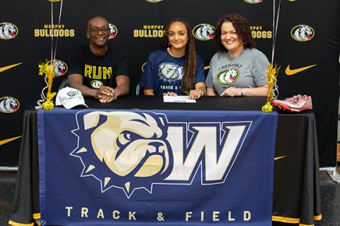 Cannon Crompton/sports@cherokeescout.com Murphy High School senior track athlete Corrine Cotton (middle) signed a letter of commitment to continue her athletic and academic career at Wingate University on Monday morning. She will be going from the Murphy Bulldogs to the Wingate Bulldogs. Cotton plans on majoring in pre-pharmacy at Wingate. She is joined by her father, Duane Cotton (left), and mother, Nicole Cotton (left).