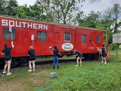 Photos by Anngee Quinones-Belian/Staff Correspondent  Members of the Mayor’s Rising Stars cleaned the red train caboose at the L&N Depot in downtown Murphy on Friday in preparation for the model train show coming up Saturday.