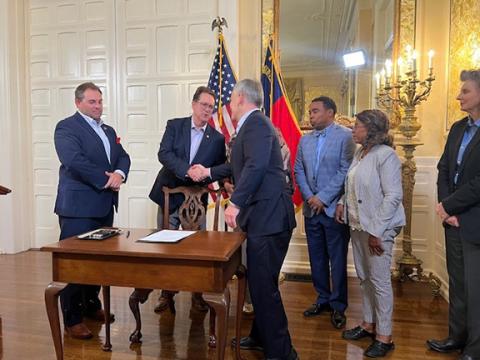 Bipartisanship: Democratic Gov. Josh Stein and N.C. Sen. Kevin Corbin (R-Franklin) shake hands after N.C. Senate Bill 124 was signed into law to make state hiring easier.